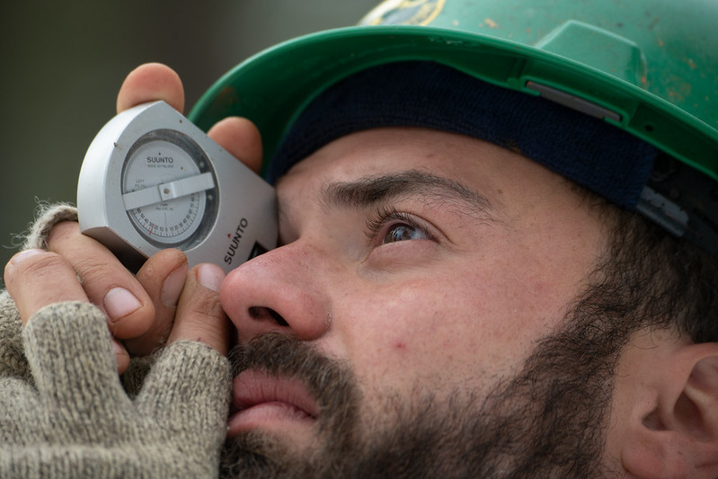Forester holding a clinometer to his eye and looking up to measure the height of a tree